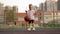 Happy preschooler in white t-shirt and shorts bounces ball on basketball court