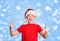 Happy preteen boy in santa hat making thumb up gesture on holiday Christmas background.