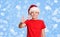 Happy preteen boy in santa hat making thumb up gesture on holiday Christmas background.
