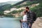 Happy preteen girl with father on hiking trip on summer holiday, looking at lake scenery.