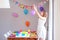 Happy preteen girl setting up table and hanging up balloons decorating house preparing to kids birthday party.