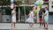 Happy preteen kids of different nationalities holding colorful balloons in hands, skipping on chinese jump rope in