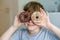 Happy preteen school boy eating sweet donut indoor. Blond child in domestic kitchen or in school canteen Cute kid and