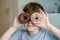 Happy preteen school boy eating sweet donut indoor. Blond child in domestic kitchen or in school canteen Cute kid and