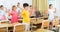 Happy preteen schoolchildren performing physical exercises in class