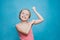 Happy pretten girl do sports and show muscles biceps on blue background.