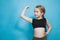 Happy pretten girl do sports and show muscles biceps on blue background.