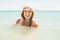 Happy pretty blonde bathing into the sea with hat