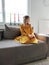 Happy pretty child girl in yellow dress on sofa at home