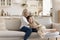 Happy pretty grandma hugging cheerful teen granddaughter on home sofa