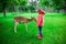 Happy pretty little girl in rubber boots feeds deers in the nature park at autumn