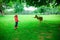 Happy pretty little girl in rubber boots feeds deers in the nature park at autumn