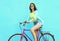 Happy pretty smiling woman rides a bicycle over colorful blue background