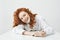 Happy pretty young girl with foxy hair smiling looking at camera sitting at table over white background.