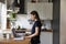 Happy pretty young renter girl using laptop in modern kitchen