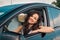 Happy pretty young woman leaning out of car window traveling on holiday road trip. Travel, lifestyle, transport concept