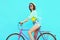 Happy pretty young woman rides a bicycle over colorful blue background