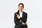 Happy professional asian female manager, businesswoman in suit showing announcement, smiling and pointing finger left at