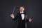 Happy professional conductor with baton on black background