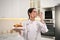 Happy professional confectioner with cake showing gesture in kitchen