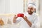 Happy professional confectioner holding cake in kitchen