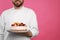 Happy professional confectioner in uniform holding delicious cake on pink background, closeup. Space for text