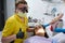 Happy professional male dentist thumbs up while performs examination of a female patient oral cavity in dentistry clinic