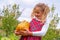 Happy proud little girl wearing a flannel dress and holding a pumpkin in a farm