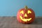 Happy Pumpkin for Halloween, carved and lighted, that`s on a burlap table with blue background with room or space for copy, text