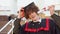 Happy red -haired curly guy with braces stands in a master's mantle and holding on to a hat and a diploma