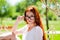 A happy red-haired girl adjusts her glasses in a large black frame, sitting in a gazebo in nature with Boke.