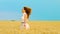 Happy red haired girl running in golden wheat field