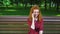 Happy red haired girl talking to friend on mobile phone in park