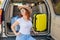 Happy red-haired woman in a cowboy hat and sunglasses going on a car trip around the country. Girl sitting in the trunk