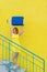 A happy red-haired woman in a yellow dress is walking down the stairs and joyfully swing a blue suitcase. The girl is