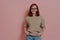 Happy redhaired female student in spectacles smiling at camera, isolated on pink background