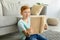 Happy redhead boy sitting on floor at home, reading book