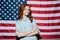 Happy redhead young lady standing over USA flag