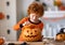 Happy redheaded boy in  costume laughs and with  pumpkin Jack o lantern   during a Halloween celebration