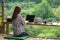 Happy relaxed asian young woman sitting and working on a laptop in the midst of nature