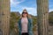 Happy, relaxed blond woman wearing sunglasses stands between two saguaro cactus cacti in Arizona, wearing casual clothing