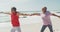 Happy and relaxed hispanic senior couple practicing yoga on beach