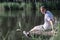 Happy relaxed man sitting on wooden pier on a lake enjoying a sunny summer day surrounded by greenery and trees looking