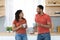 Happy relaxed young african american guy and woman in same red t-shirts with cups enjoy drink and free time