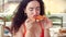 Happy Relaxed young Italian woman in red dress holding slice of a pie eagerly eating and enjoying Italian pizza while