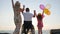 Happy rest, invalid with wife and daughter raise their hands up with colorful air balloons near sea, family with child