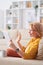 Happy restful mature woman in casualwear relaxing on couch with tablet