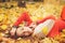 Happy resting girl portrait, lying in autumn maple leaves in park, closed eyes, dressed in fashion sweater