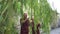 Happy retired Asian senior couple laughing under green willow tree