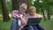 Happy retired man and woman sitting on grass and watching movie on laptop pc